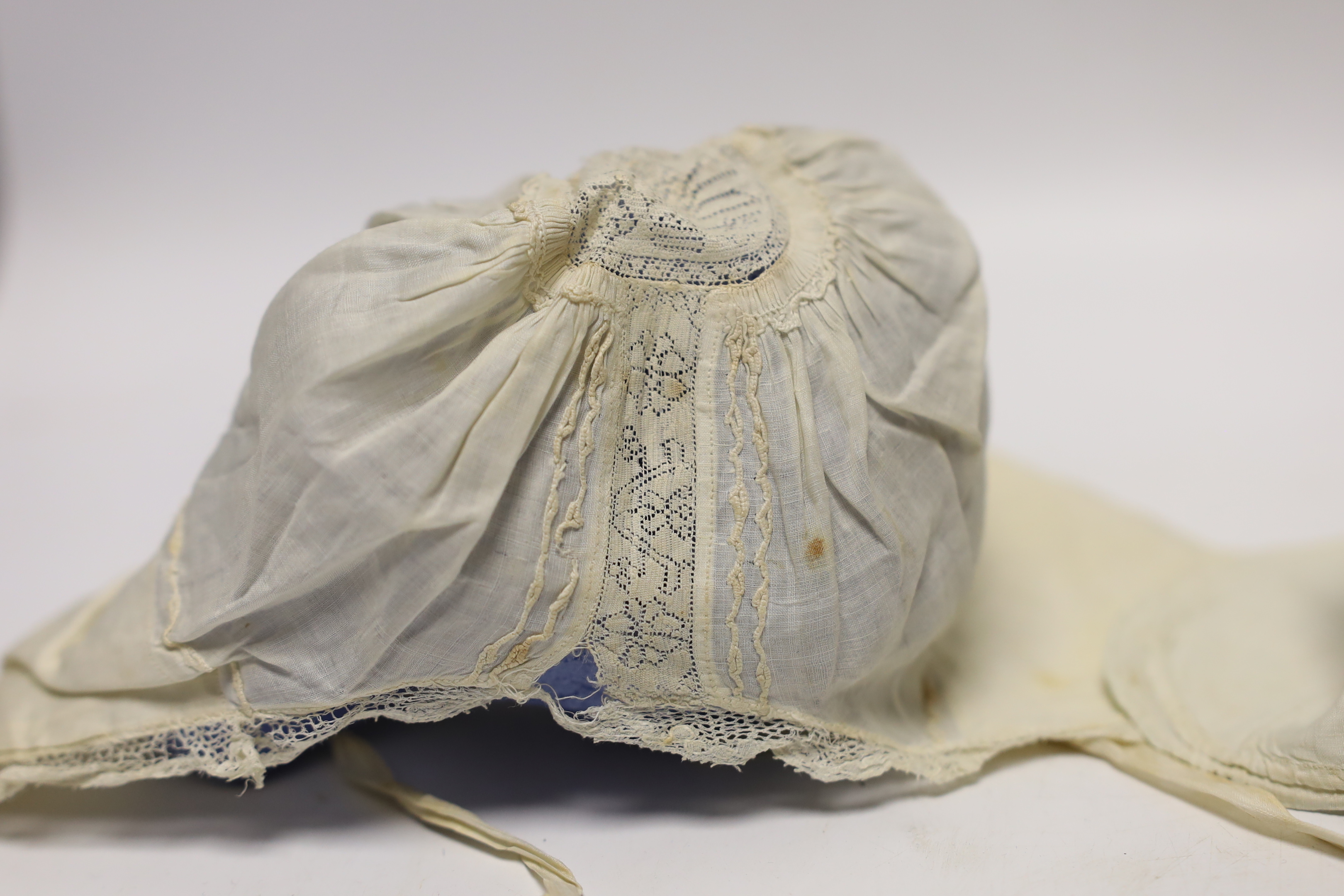 An early 18th century Hollie point insertion baby’s linen vest, three baby bonnets with Hollie point insertions and an early 18th century pair of Flemish bobbin lace lappets, a partly finished needlepoint length of lace,